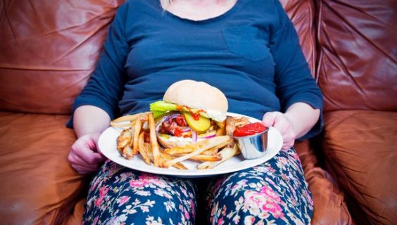 woman sitting on couch with plate full of burger and fries