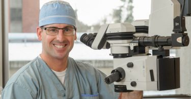 Dr. David Albiani, head of Providence Health Care’s (PHC) ophthalmology department, next to a microscope.