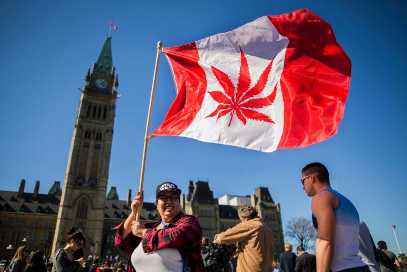This file photo taken on April 20, 2016 shows a woman waving a flag with a marijuana leaf on it next to a group gathered to celebrate National Marijuana Day on Parliament Hill in Ottawa. (CHRIS ROUSSAKIS / AFP/GETTY IMAGES)