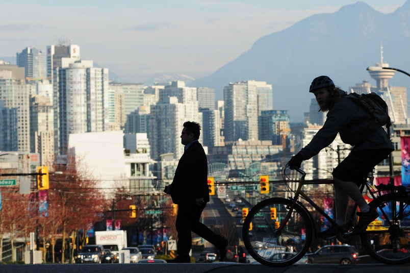Skyline shot of Vancouver buildings downtown with silhouette of cyclist and biker.