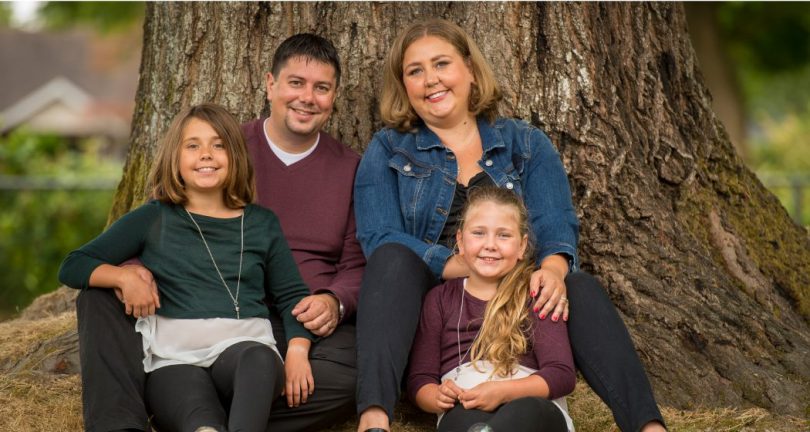 Hayley Atkinson, kidney transplant recipient, sitting in front of tree with husband Bill and two daughters.