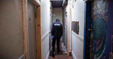 A security guard checks the run-down shared bathroom at the Sahota-owned Regent Hotel. (Photo Credit: DARRYL DYCK/THE GLOBE AND MAIL)