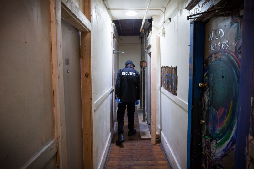 A security guard checks the run-down shared bathroom at the Sahota-owned Regent Hotel. (Photo Credit: DARRYL DYCK/THE GLOBE AND MAIL)