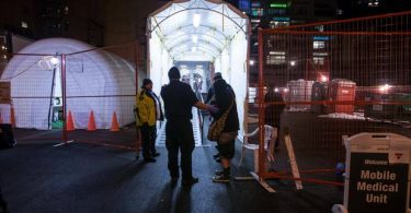A woman is helped into the Mobile Medical Unit after a suspected overdose in the Downtown Eastside on Dec. 21, 2016. (Photo Credit: BEN NELMS/THE GLOBE AND MAIL)