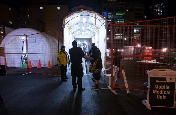 A woman is helped into the Mobile Medical Unit after a suspected overdose in the Downtown Eastside on Dec. 21, 2016. (Photo Credit: BEN NELMS/THE GLOBE AND MAIL)