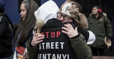 Two people embrace at a vigil held in Vancouver on the province's overdose crisis. (Photo Credit: Tina Lovgreen/CBC)