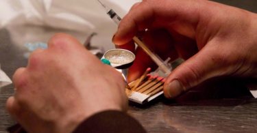 A man prepares heroin he bought on the street to be injected at the Insite safe injection clinic in Vancouver on May 11, 2011. (Photo Credit: THE CANADIAN PRESS/Darryl Dyck)