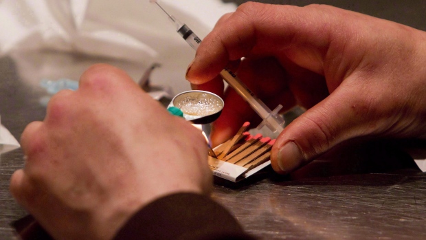 A man prepares heroin he bought on the street to be injected at the Insite safe injection clinic in Vancouver on May 11, 2011. (Photo Credit: THE CANADIAN PRESS/Darryl Dyck)