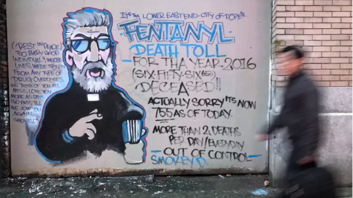 A man walks past a mural by street artist Smokey D. about the fentanyl and opioid overdose crisis, in the Downtown Eastside of Vancouver, B.C. (Photo credit: CBC News)
