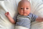 A baby born premature at St. Paul's Hospital wears a grey onesie that says #bornatstpauls