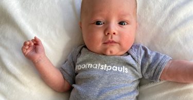 A baby born premature at St. Paul's Hospital wears a grey onesie that says #bornatstpauls