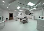 A hospital operating room with an operating table in the middle surrounded by large movable lights.