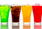 Four glasses filled with sugary drinks of different colours.