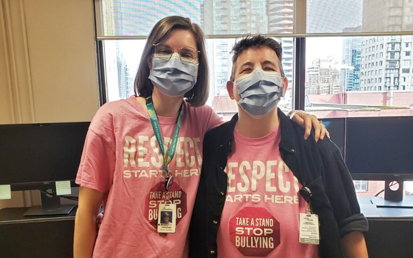 Social workers Christina Schellenberg and Jody Max stand side by side in matching pink shirts.