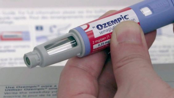 Close up image of a hand holding an Ozempic pen.