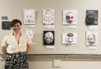 An art therapist stands by a display of eight colourful masks made by patients at Providence Health Care.