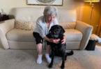 Woman smiling at black lab guide dog after regaining partial sight